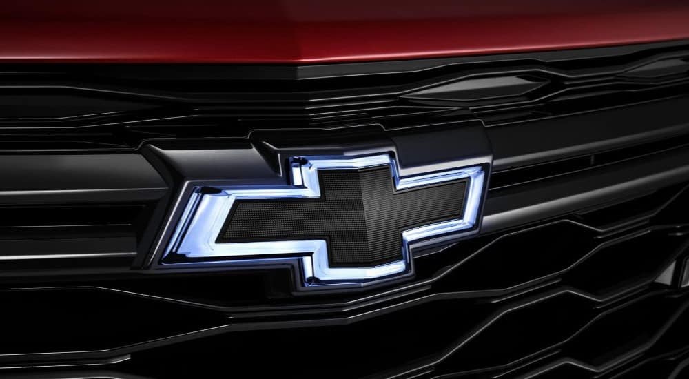 A close up shows the Chevy logo on the grille of a red 2024 Chevy Equinox RS.