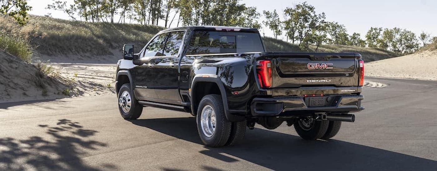 A black 2024 GMC Sierra 3500 HD Denali is shown from the rear at an angle.